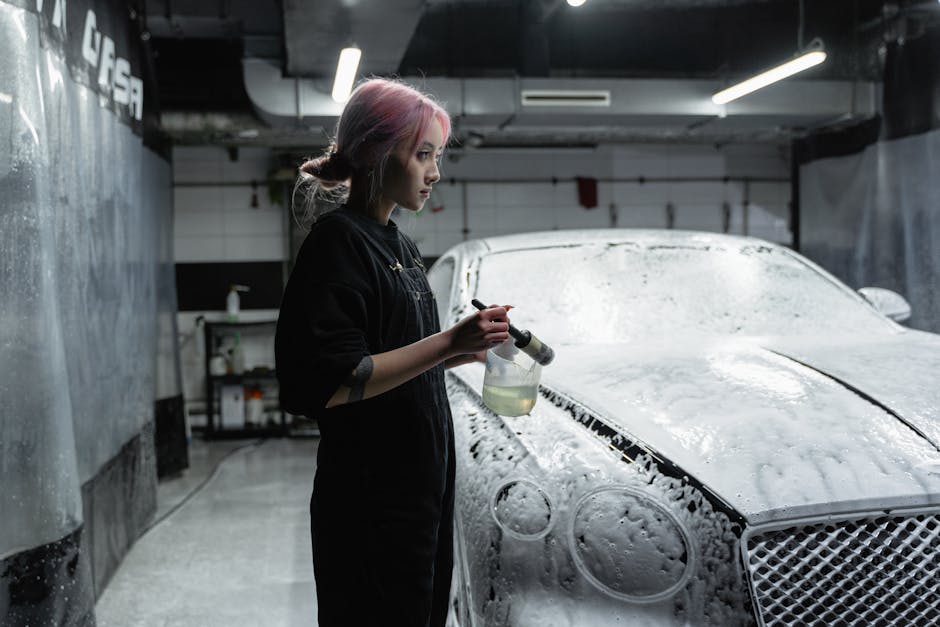 Asian woman washing luxury car in indoor car wash with foam.